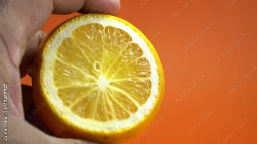 closeup of holding a half cut sliced orange on vibrant orange background 4K. closeup of holding a half cut sliced orange on vibrant orange background 4K.