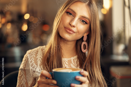 Beautiful young woman sitting in coffee shop enjoying her drink