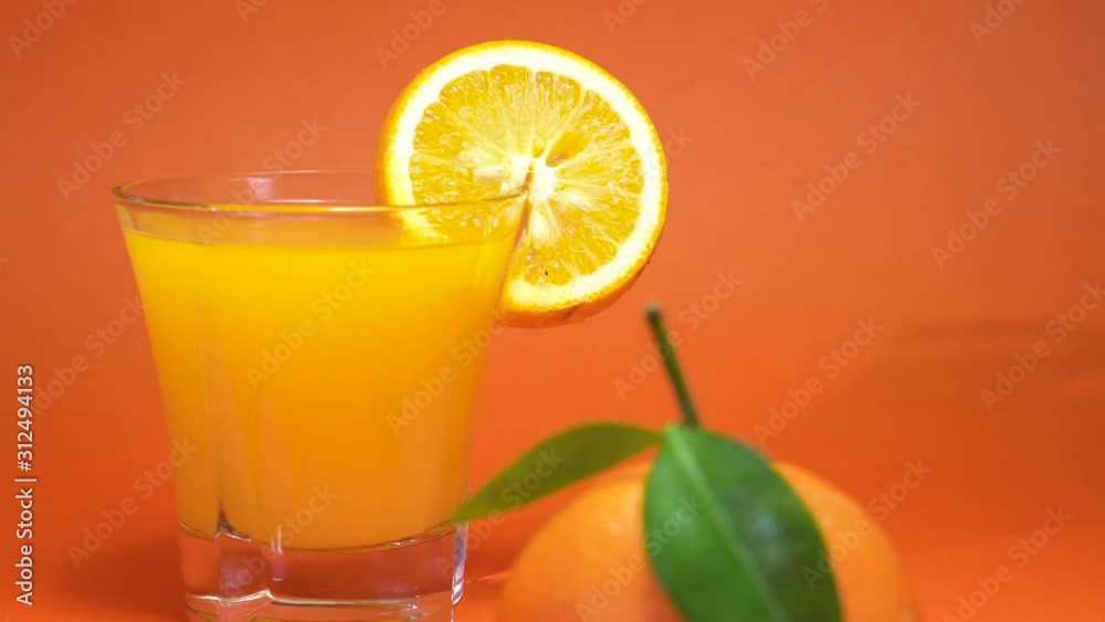 orange juice in a glass with orange slice and a full orange in foreground 4K orange juice in a glass with orange slice and a full orange in foreground 4K
