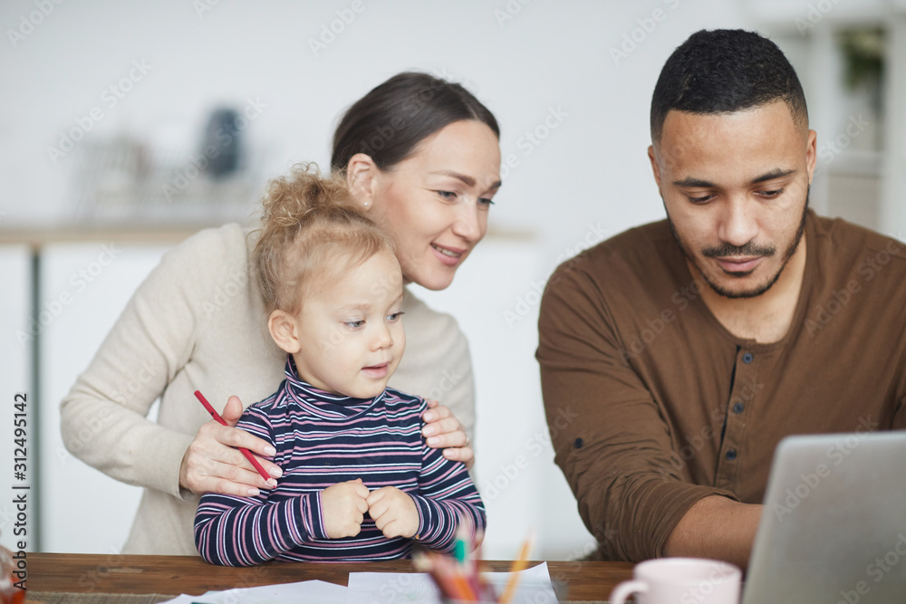 Portrait of smiling mixed-race family using laptop together while shopping online with little girl Portrait of smiling mixed-race family using laptop together while shopping online with little girl