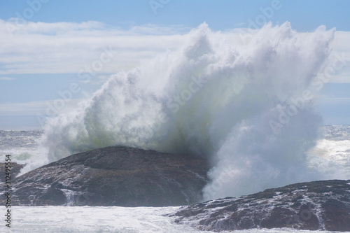 big wave crashing at the rocks of the shoreline on a sunny day on Vancouver Island