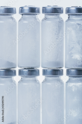 Glass medical ampoule vial for injection. Medicine is dry white drug penicillin powder or liquid with of aqueous solution in ampulla. Close up. Bottles ampule with aluminum cap on backgrounds gray.
