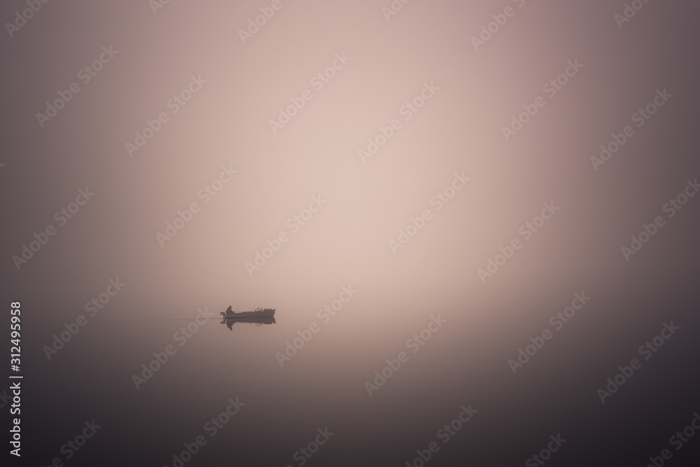 lonely fisherman on a boat in a very strong fog on the lake lonely fisherman on a boat in a very strong fog on the lake