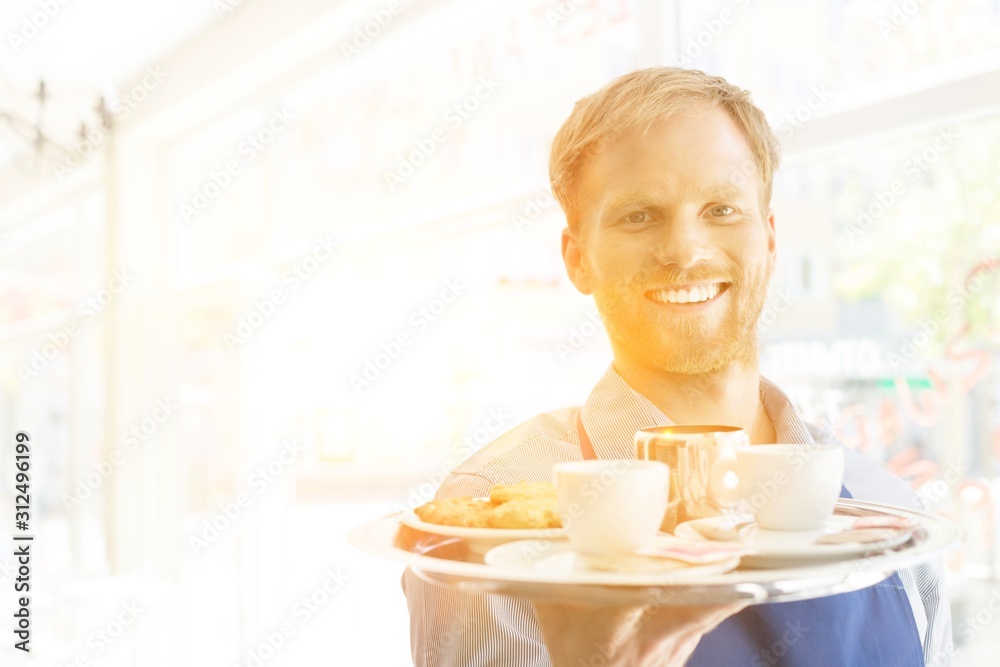 Portrait of confident young waiter serving espresso coffee at restaurant