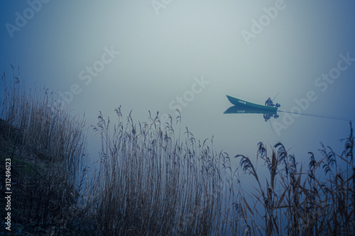 lonely fisherman on a boat in a very strong fog on the lake