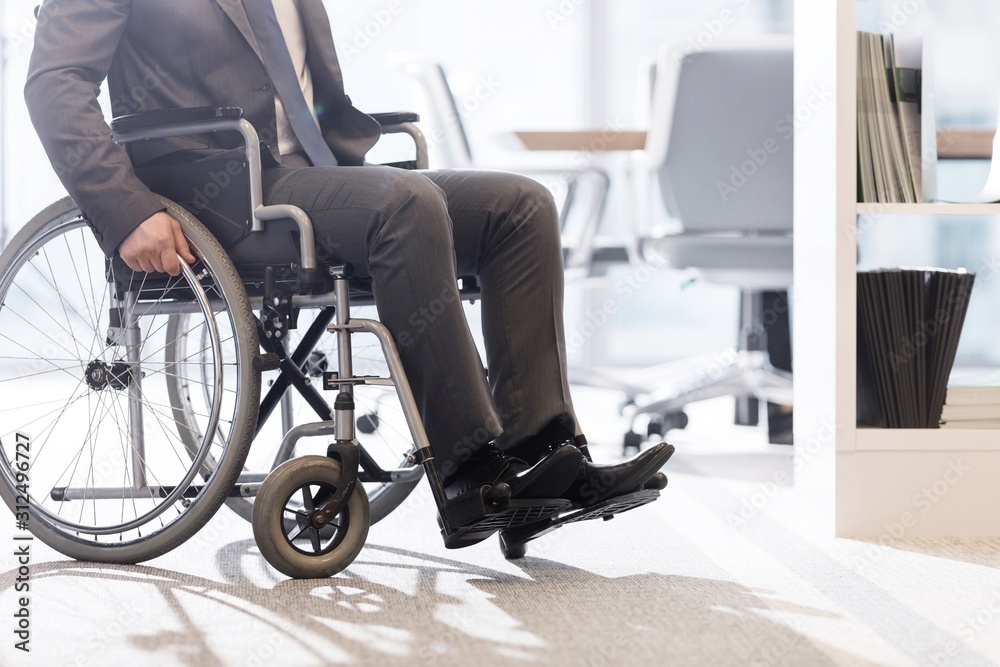 Low angle view of disabled businessman on wheelchair at modern office Low angle view of disabled businessman on wheelchair at modern office