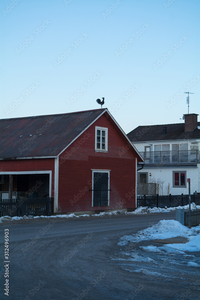 A red barn in Sweden with a black rooster statue on the roof photographed vertical A red barn in Sweden with a black rooster statue on the roof photographed vertical
