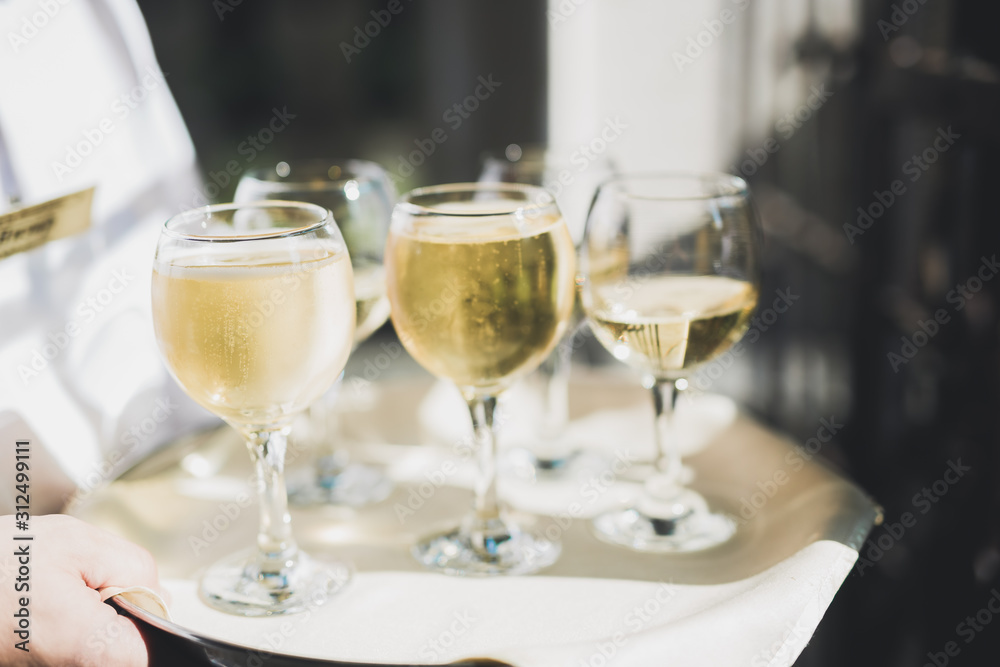 Waiter serving glasses with champagne on a tray