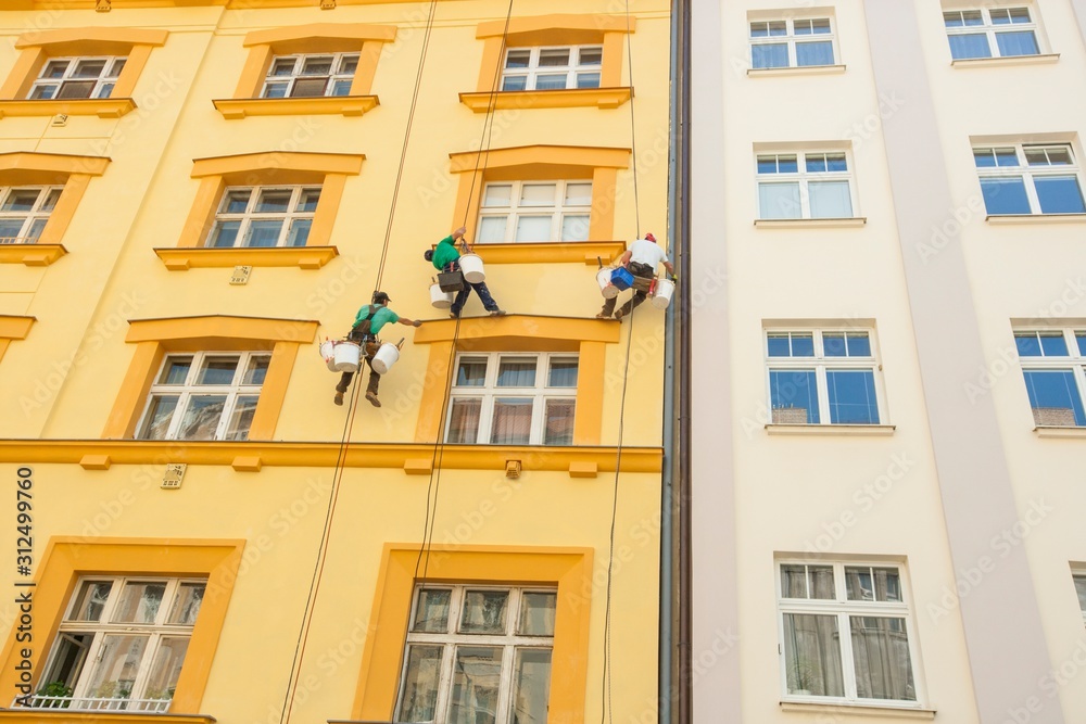 Low angle view of window washers hanging outside building