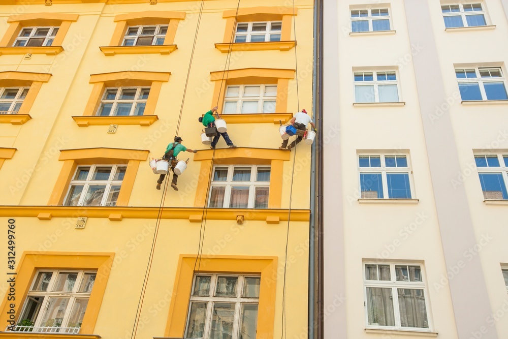 Obraz premium Low angle view of window washers hanging outside building