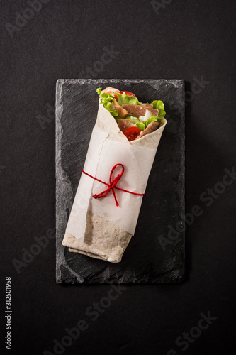 Doner kebab or shawarma sandwich on black slate background. Top view. 