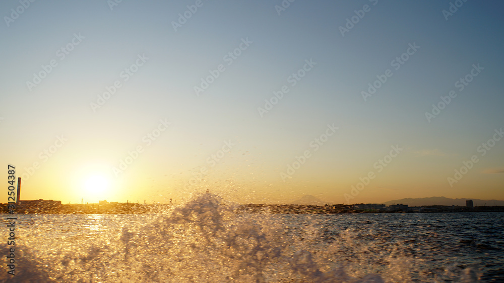 Obraz premium 波しぶきをオレンジに染める東京湾の夕日