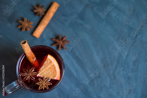 winter spicy alcoholic mulled wine based on red wine, spices and orange. on a dark background, orange slices . close-up, space for text . the view from the top