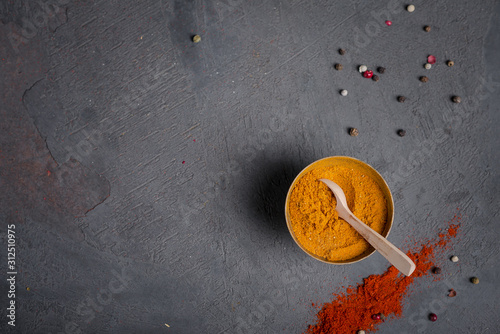 Loose curry spice in a metal bowl on a dark background and paprika with peppercorns