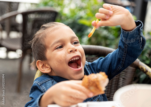 little boy eats french fries and chicken