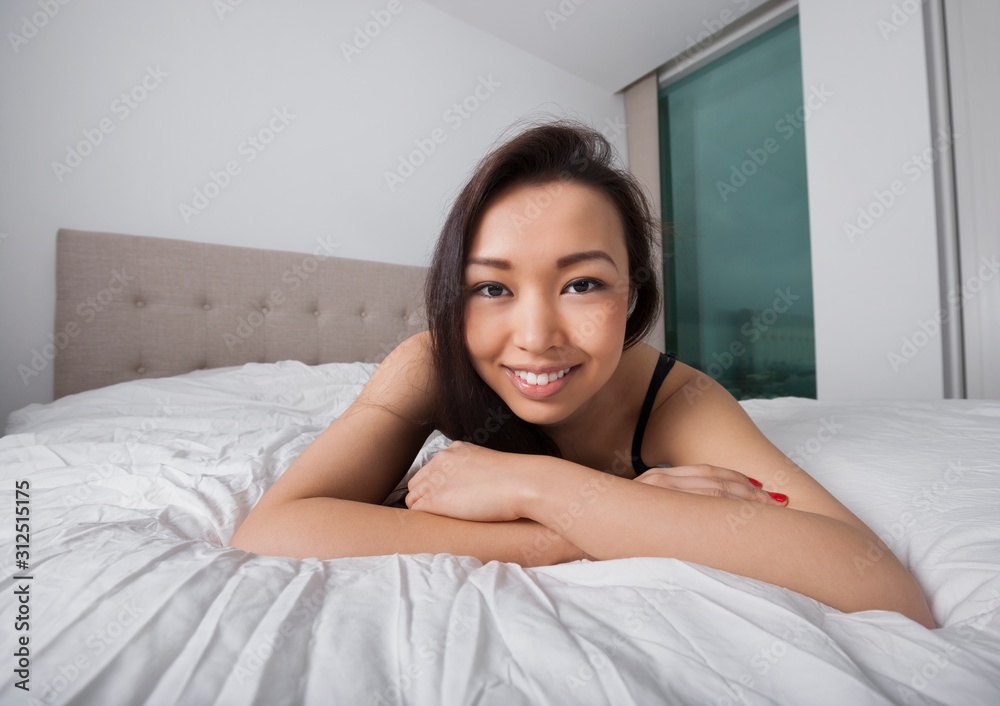 Fototapeta premium Portrait of happy young woman resting in bed