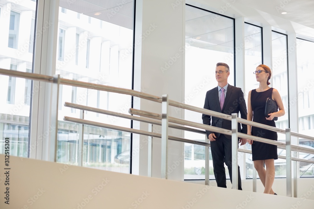 Business people walking by railing in office Business people walking by railing in office