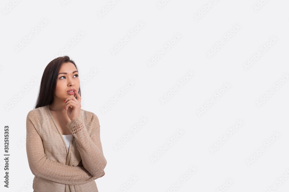 Thoughtful young woman standing against gray background Thoughtful young woman standing against gray background