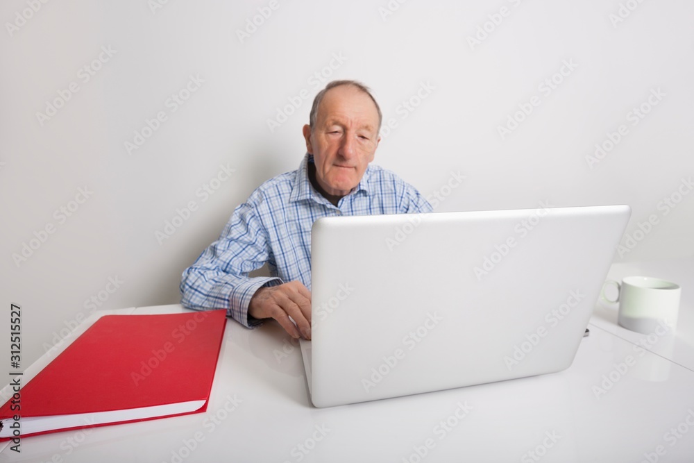 Senior businessman using laptop at office desk Senior businessman using laptop at office desk