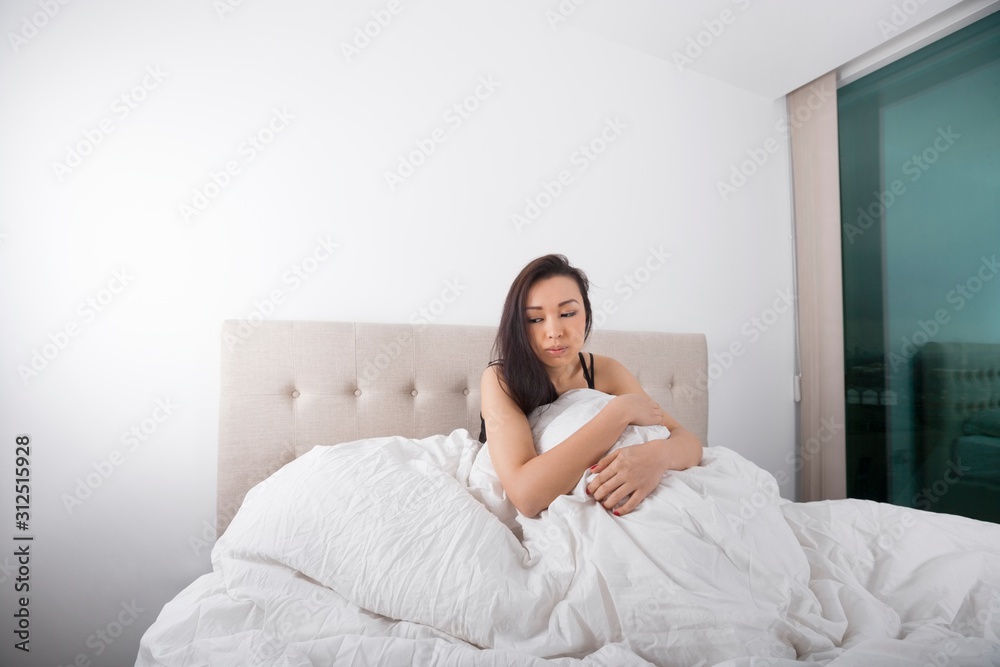 Sad young woman sitting on bed