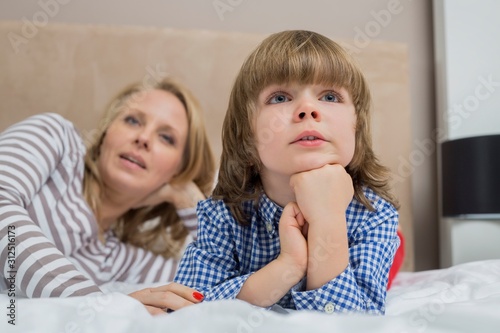 Thoughtful boy with mother in bed