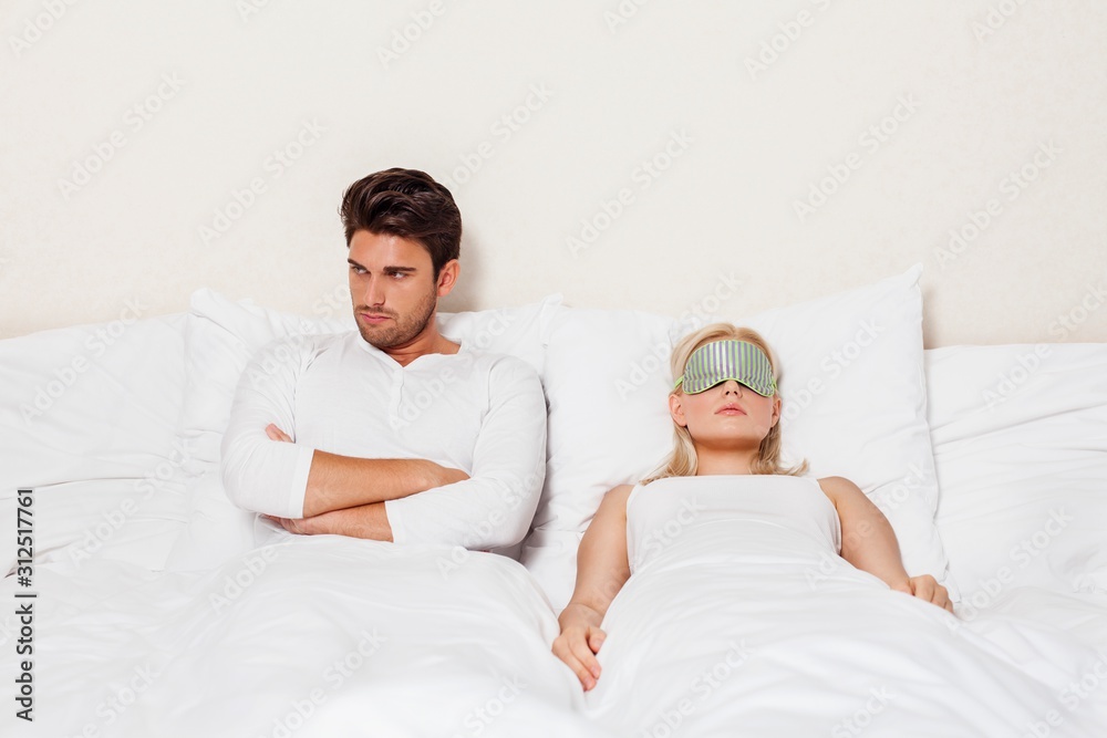 Fototapeta premium Angry young man with woman sleeping in bed