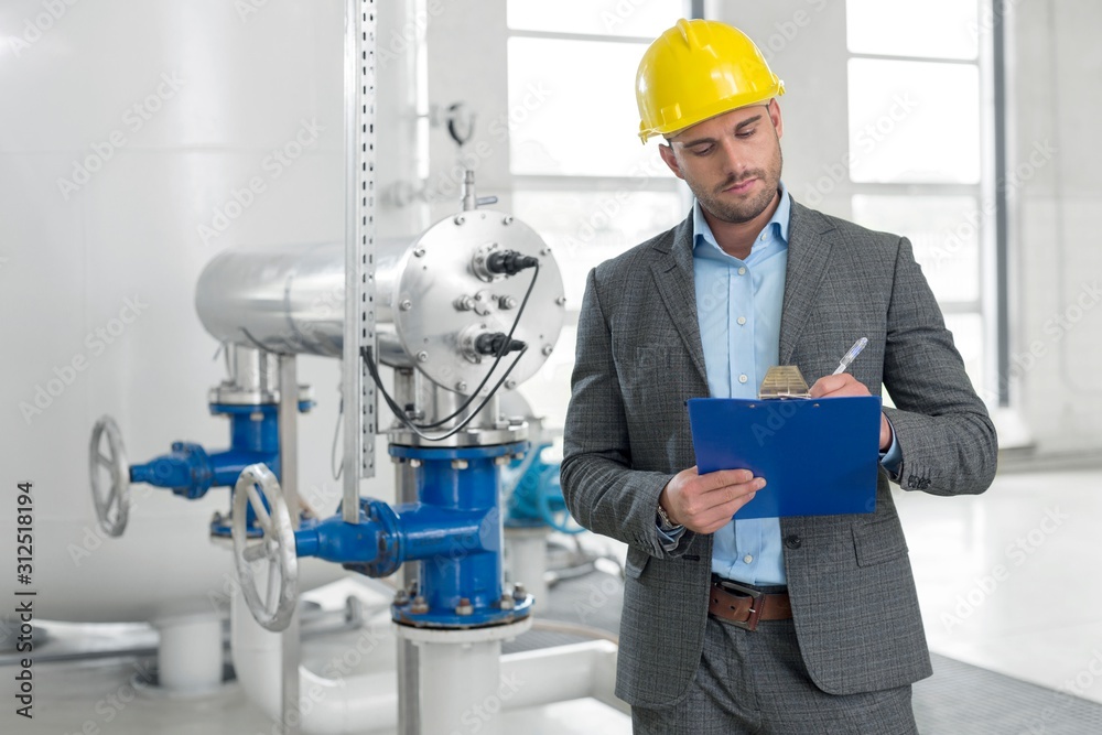 Young male manager writing on clipboard in industry Young male manager writing on clipboard in industry