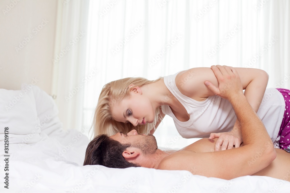 Side view of young couple cuddling in bed Side view of young couple cuddling in bed
