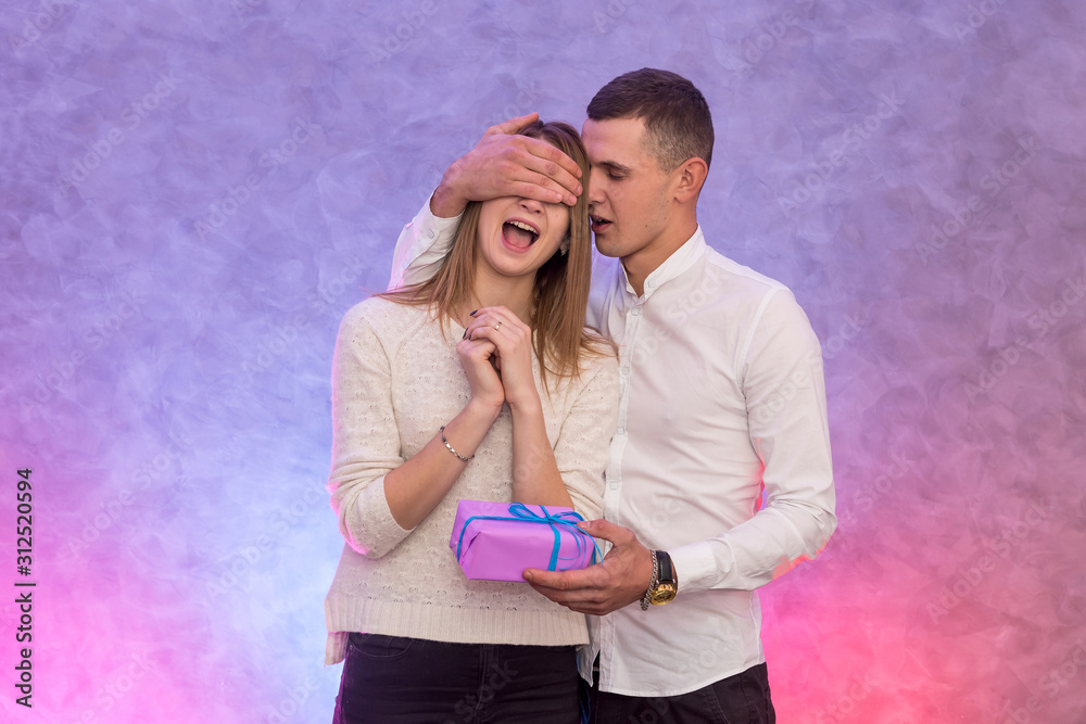 Naklejka premium Girl giving her boyfriend present studio shot. Valentine's concept.
