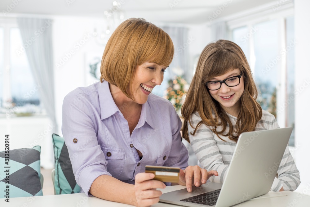 Cheerful mother and daughter shopping online at home during Christmas Cheerful mother and daughter shopping online at home during Christmas