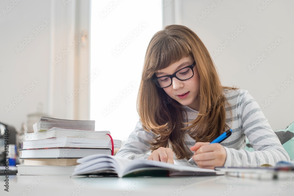 Teenage girl doing homework at table in house Teenage girl doing homework at table in house