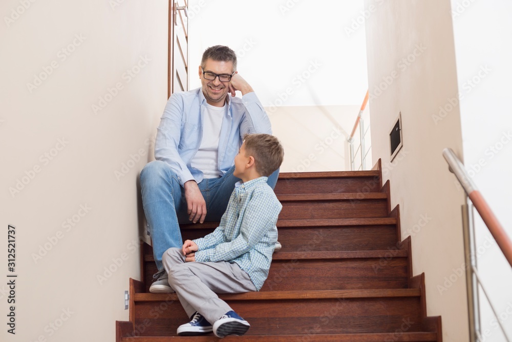 Happy father and son sitting on steps at home Happy father and son sitting on steps at home