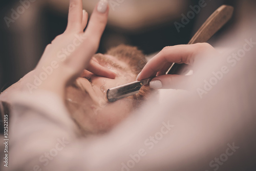 Barber master a girl with a dangerous razor works in a barbershop