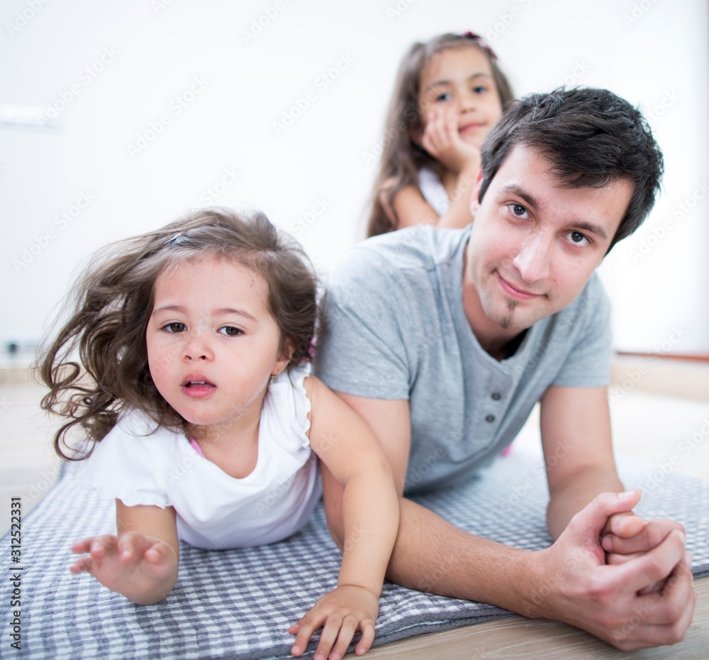 Portrait of father with daughters lying on blanket at home Portrait of father with daughters lying on blanket at home