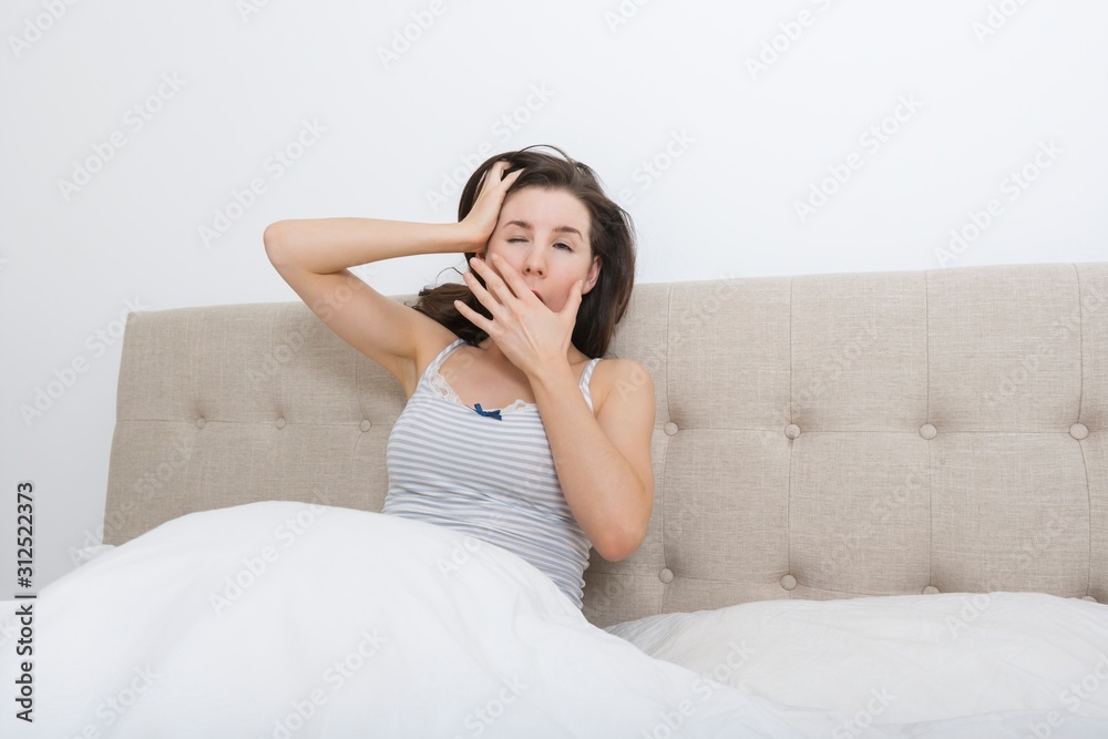 Sleepy woman yawning in bed
