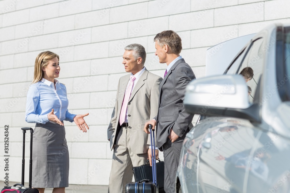 Businesspeople with luggage discussing outside car Businesspeople with luggage discussing outside car