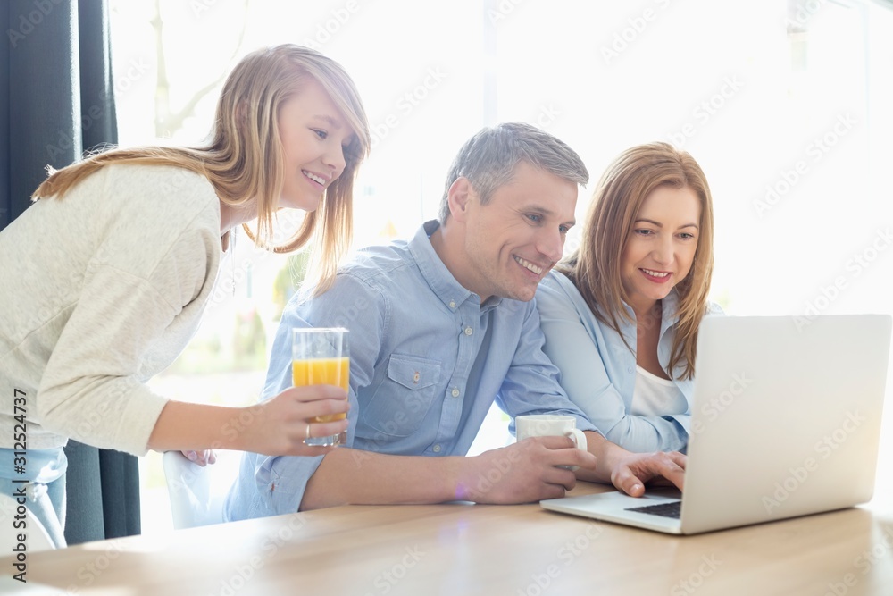 Happy parents with daughter using laptop at home