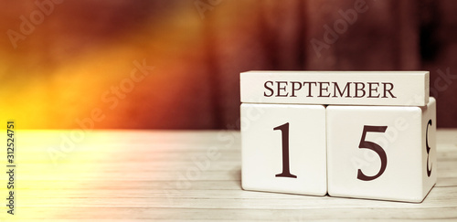 Calendar reminder event concept. Wooden cubes with numbers and month on September 15 with sunlight.
