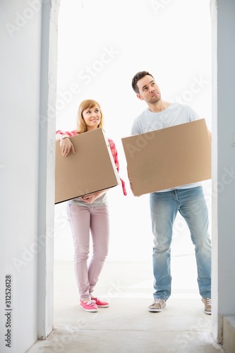 Full-length of couple with cardboard boxes standing in front of entrance