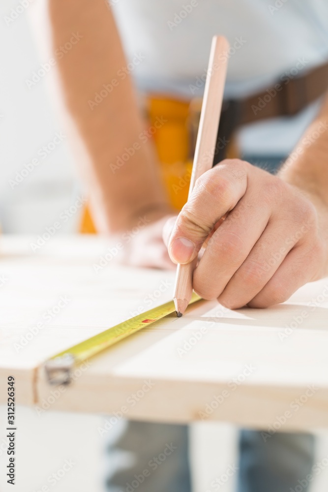 Midsection of carpenter marking table with measure tape Midsection of carpenter marking table with measure tape