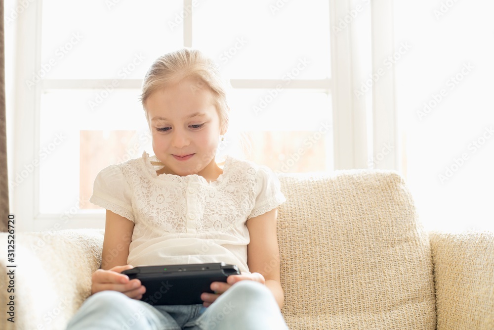 Cute girl playing hand-held video game at home Cute girl playing hand-held video game at home