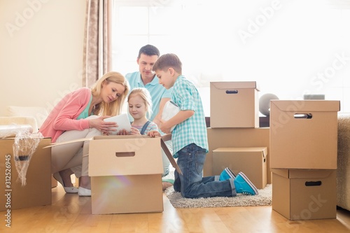 Family unpacking cardboard boxes at new home