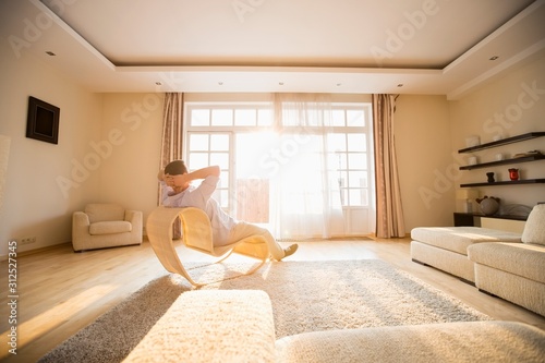 Bild auf Leinwand Rear view of man relaxing on modern chair at home