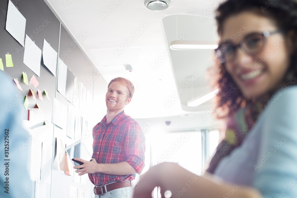 Fototapeta premium Smiling businessman with female colleague in foreground at creative office