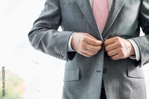 Midsection of mature businessman buttoning his blazer