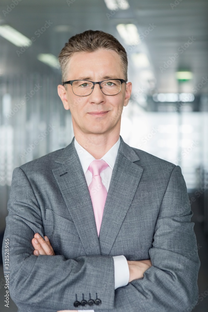 Portrait of middle-aged businessman standing with arms crossed in office Portrait of middle-aged businessman standing with arms crossed in office