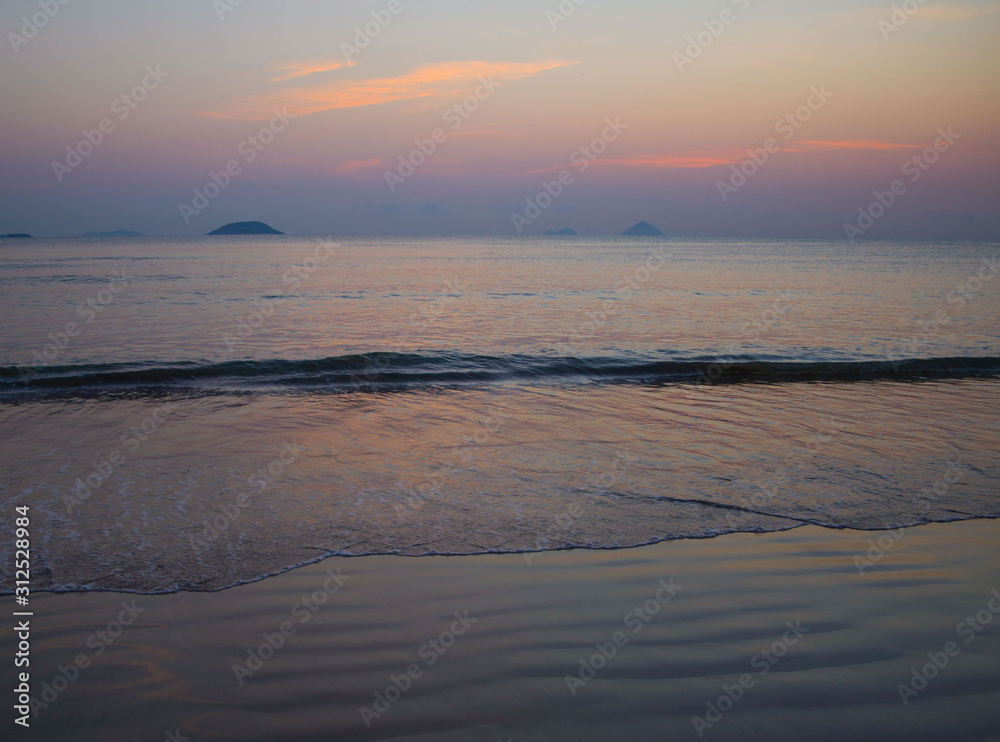 a girl coming to the beach from the sea water on the background of the rising sun