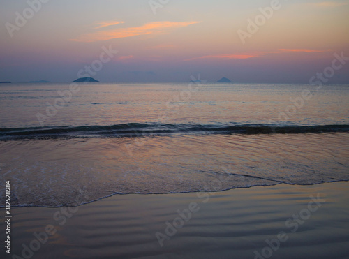 a girl coming to the beach from the sea water on the background of the rising sun