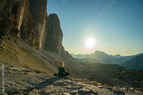 Woman tourist looking to Mountainous landscape in evening in Three Peaks Nature Park in Italian dolomite Alps