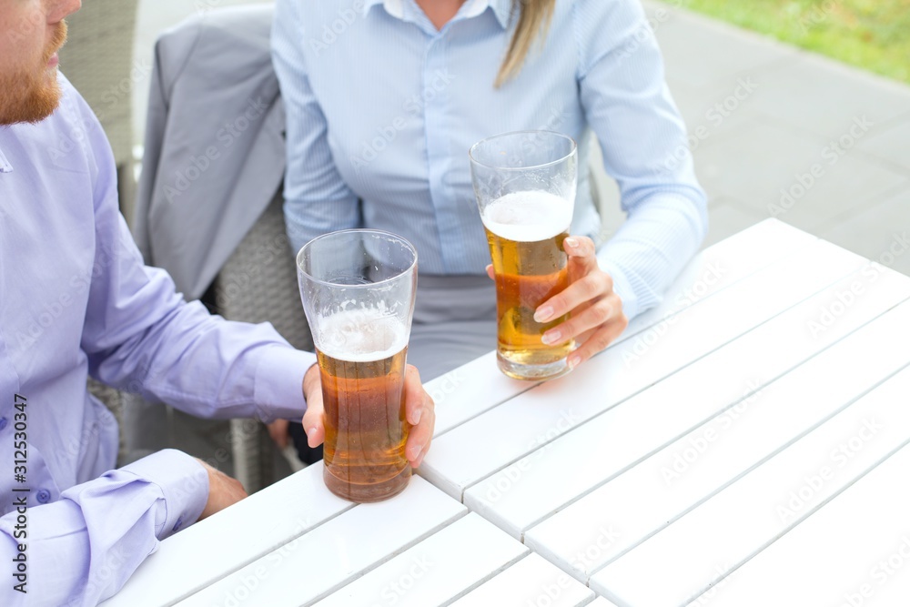 Midsection of business couple holding beer glasses at outdoor restaurant Midsection of business couple holding beer glasses at outdoor restaurant